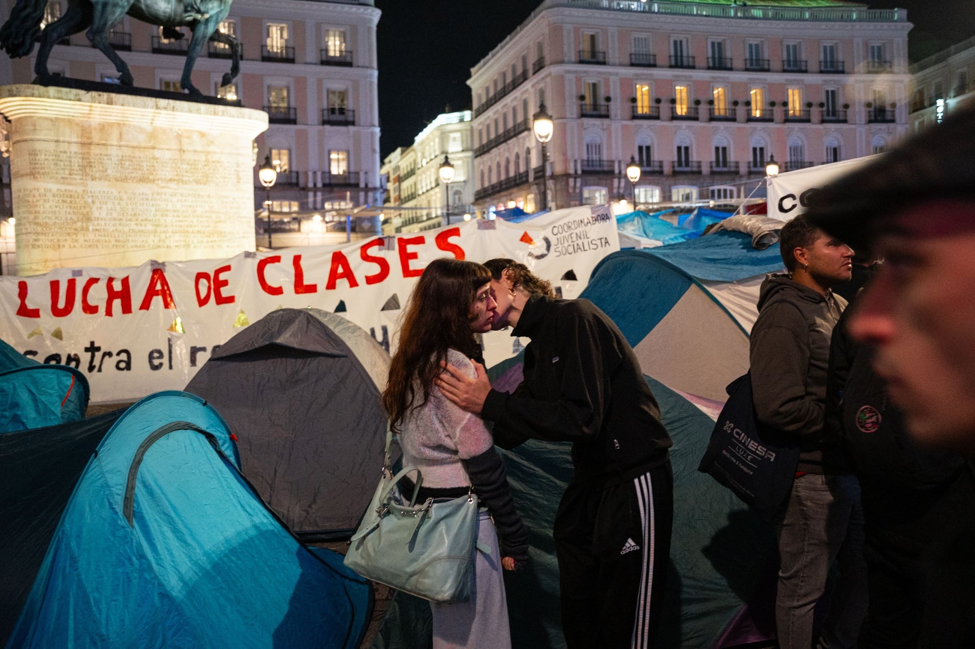A couple is kissing during an encampment has been set up for days by protesters at Puerta del Sol in Madrid.