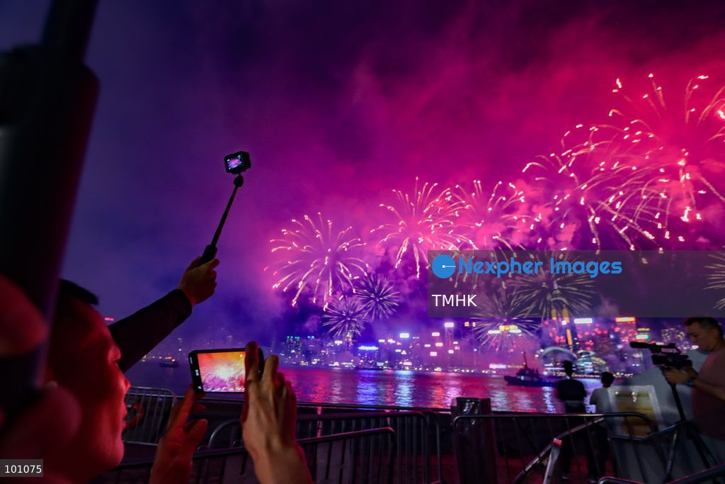 Crowds of citizens and tourists pack the waterfront promenade outside the Hong Kong Cultural Centre in Tsim Sha Tsui, holding up their smartphones to film and photograph the fireworks display illuminating Victoria Harbour during the 77th National Day celebrations on October 1, 2026 in Hong Kong. (Photo by Gordon Choi/TMHK via Nexpher Images)