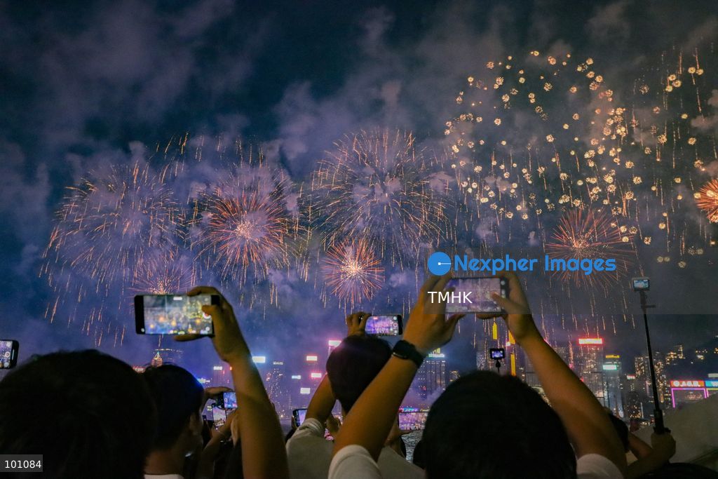 Crowds of citizens and tourists pack the waterfront promenade outside the Hong Kong Cultural Centre in Tsim Sha Tsui, holding up their smartphones to film and photograph the fireworks display illuminating Victoria Harbour during the 77th National Day celebrations on October 1, 2026 in Hong Kong. (Photo by Gordon Choi/TMHK via Nexpher Images)