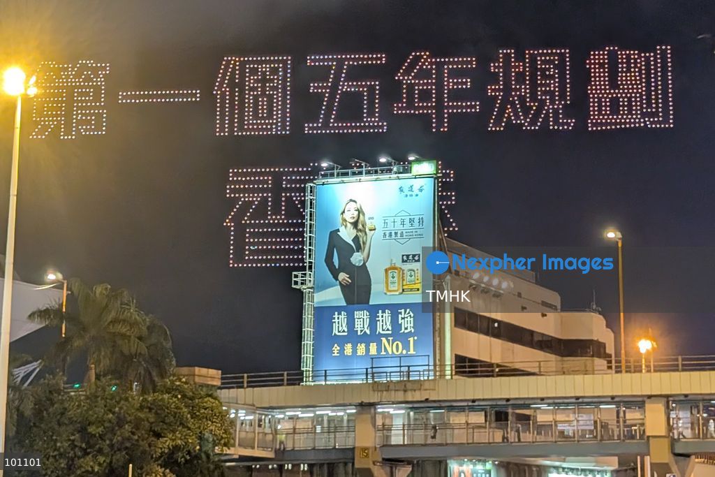 A close-up view captured from the Cross-Harbour Tunnel Bus-Bus Interchange shows illuminated drones assembling to form the Chinese characters for "First Five-Year Plan Hong Kong" above the Hung Hom waterfront on October 2, 2026 in Hong Kong, highlighting the city's strategic development blueprint during the 77th National Day celebrations. (Photo by Judy Cheung/TMHK via Nexpher Images)