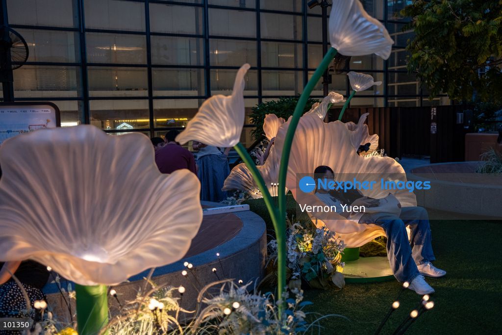 A girl sitting on a lit flower shaped seat at an outdoor area of a shopping mall on October 3, 2026 in Hong Kong (Photo by Vernon Yuen/Nexpher Images)