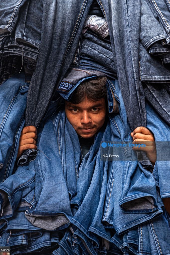 KALIGANJ, DHAKA, BANGLADESH, OCTOBER 7, 2026: Garment traders and workers transport large bundles of denim clothing through a busy market in Kaliganj, Dhaka. Jeans and other garments are stacked outside shops and moved through crowded streets by handcart, bicycle and truck for distribution and sale. The market forms part of the local apparel trade, where workers and traders handle large volumes of clothing moving between wholesalers, retailers and buyers. Photo by Bipul Ahmed / JNA Press. (Photo by Bipul Ahmed/JNA Press via Nexpher Images)