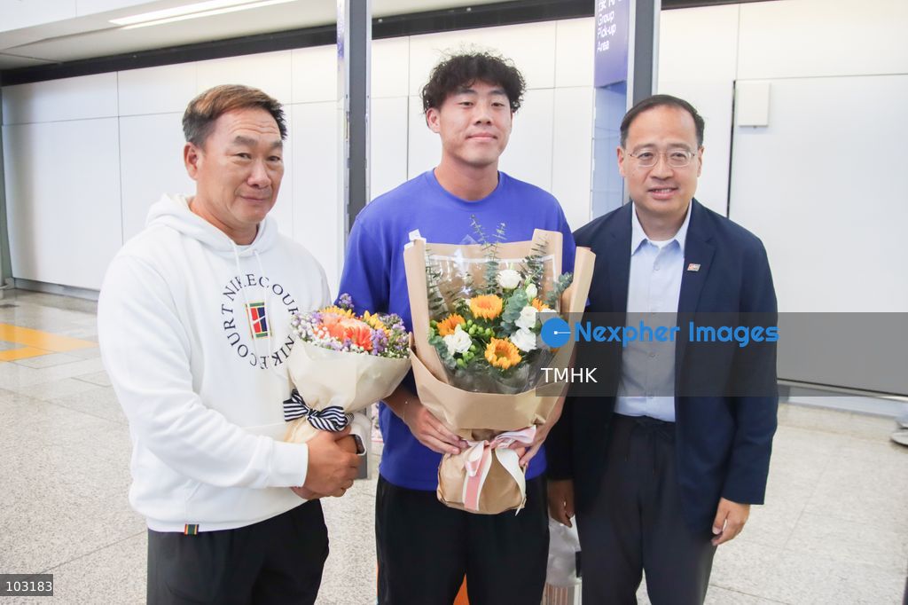 Hong Kong, China tennis player Coleman Wong poses for photographs with Hong Kong, China Tennis Association President Michael Cheng and another guest upon his arrival at Hong Kong International Airport on October 8, 2026. Wong receives flowers following his men's singles tennis gold medal victory at the Asian Games. (Photo by Gordon Choi/TMHK via Nexpher Images)