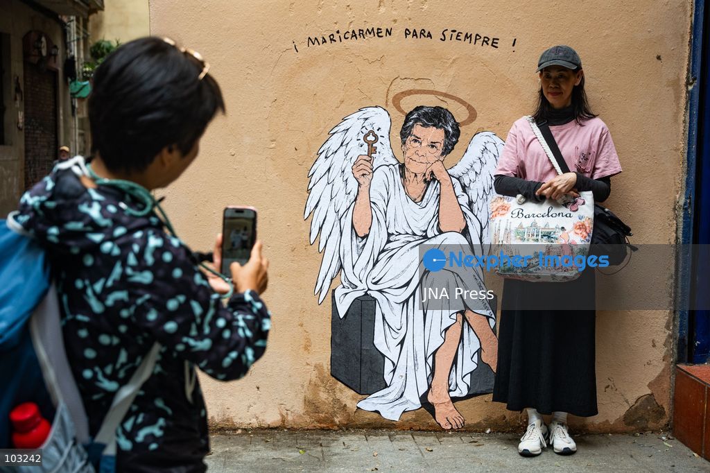 BARCELONA, SPAIN, OCTOBER 8, 2026: Tourists and local residents photograph a mural by urban artist TVBoy depicting Maricarmen Abascal as an angel holding a key in Barcelona. Titled "Maricarmen Para Siempre," the artwork pays tribute to the elderly woman whose eviction and subsequent death sparked widespread housing protests across Spain. Abascal became a symbol of the movement demanding stronger tenant protections and measures against evictions. Photo by Marc Asensio Clupes / JNA Press. (Photo by Marc Asensio Clupes/JNA Press via Nexpher Images)