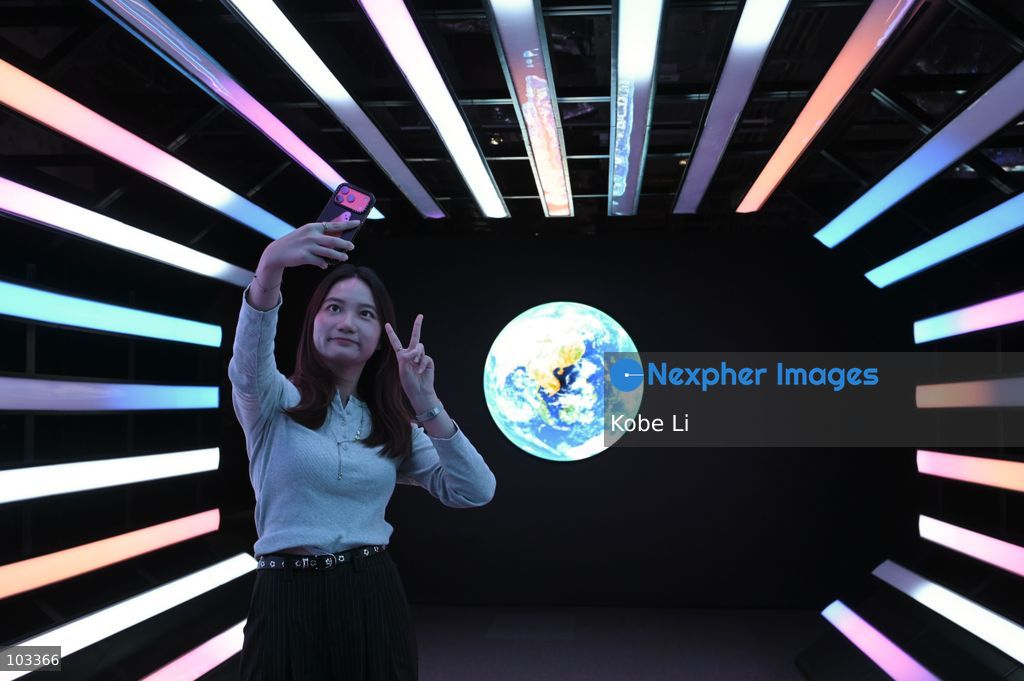 A visitor posing photo with a large display depicting Earth at "Fly Me to the Moon – A 380,000 km Odyssey" exhibition at K11 MUSEA on October 9, 2026 in Hong Kong. (Photo by Kobe Li/Nexpher Images)