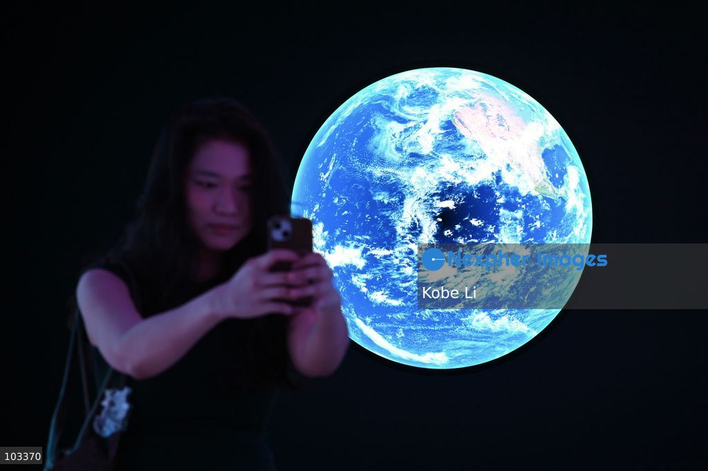 A visitor posing photo with a large display depicting Earth at "Fly Me to the Moon – A 380,000 km Odyssey" exhibition at K11 MUSEA on October 9, 2026 in Hong Kong. (Photo by Kobe Li/Nexpher Images)