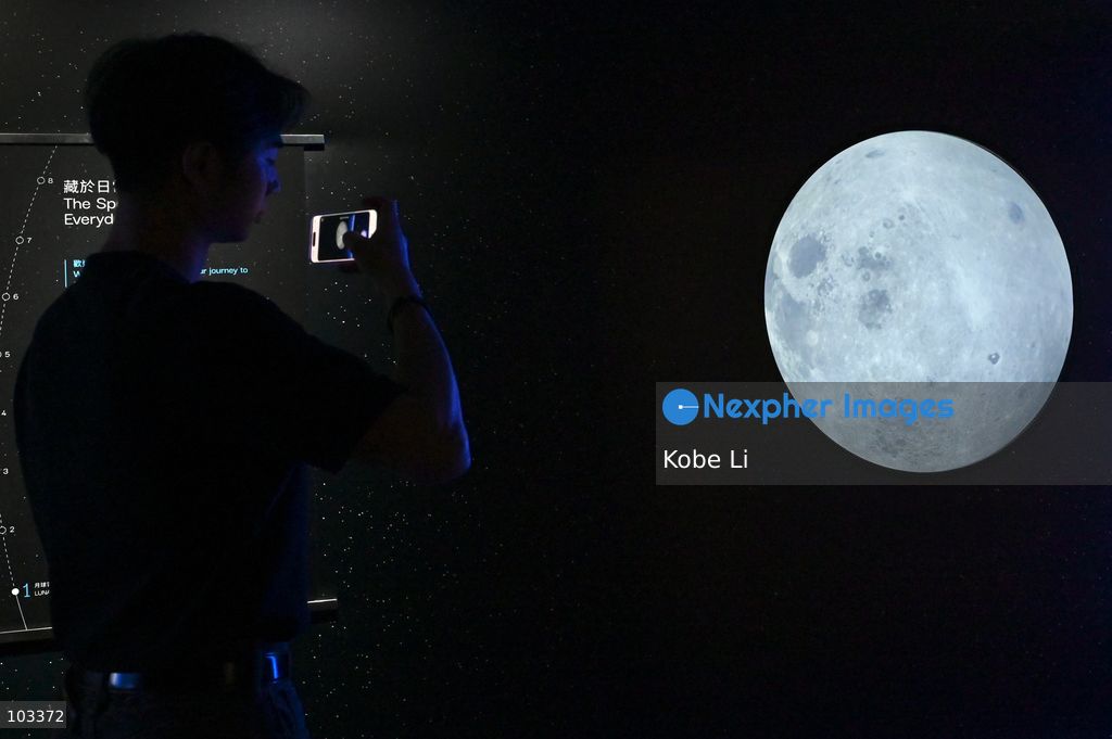 A visitor taking photo with a large display depicting moon at "Fly Me to the Moon – A 380,000 km Odyssey" exhibition at K11 MUSEA on October 9, 2026 in Hong Kong. (Photo by Kobe Li/Nexpher Images)