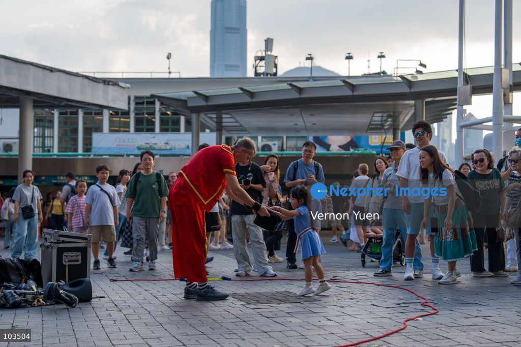 A street performer receiving money from a little girl on October 10, 2026 in Hong Kong. (Photo by Vernon Yuen/Nexpher Images)