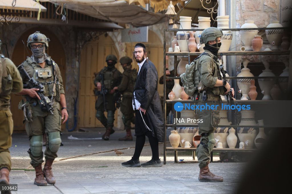 HEBRON, OCCUPIED WEST BANK, OCTOBER 10, 2026: Israeli settlers enter Hebron's Old City under the protection of Israeli forces during an organized visit to the area. Israeli soldiers deployed along streets and around the group as settlers moved through the Old City, where Israeli settlers and Palestinian residents live in close proximity amid longstanding tensions and movement restrictions. Photo by Mosab Shawer / JNA Press. (Photo by Mosab shawer/JNA Press via Nexpher Images)
