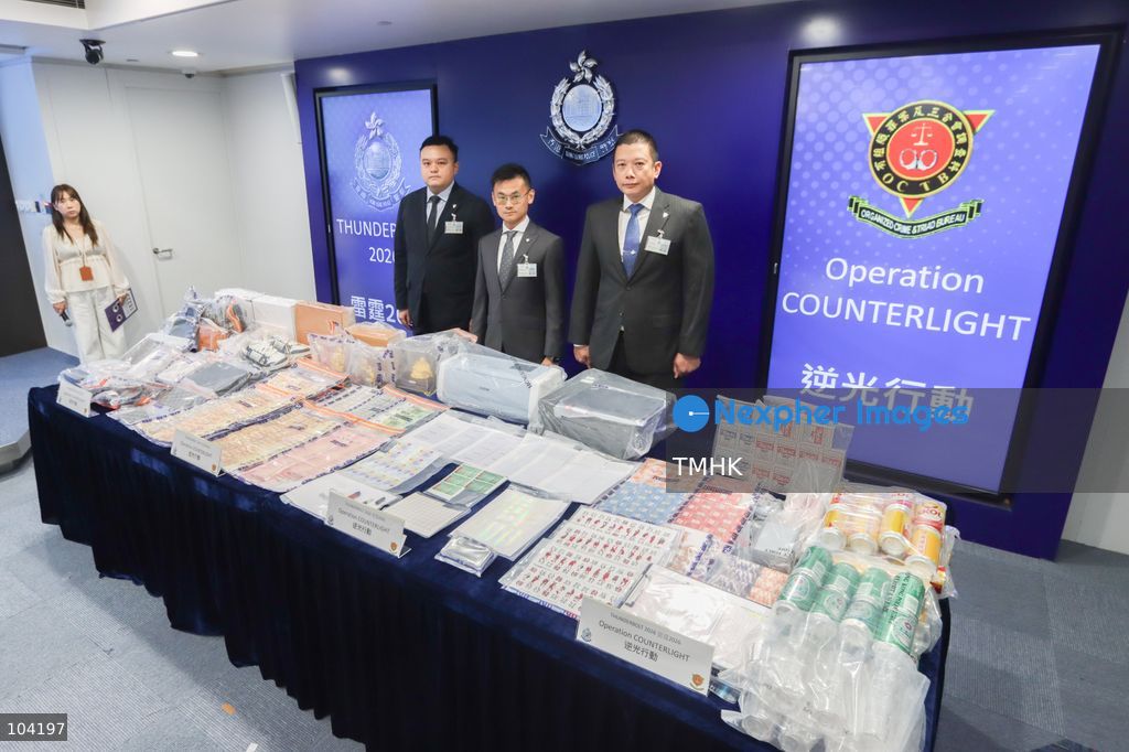 Superintendent Chow Tsz-hin of the Organised Crime and Triad Bureau, Chief Inspector Ho Yan-kit and Senior Inspector Chan Pak-kin pose for photographs in front of seized exhibits during a press briefing on a crackdown against an alleged non-ethnic Chinese criminal syndicate involved in loan sharking and illegal gambling in Hong Kong on October 10, 2026. (Photo by Gordon Choi/TMHK via Nexpher Images)