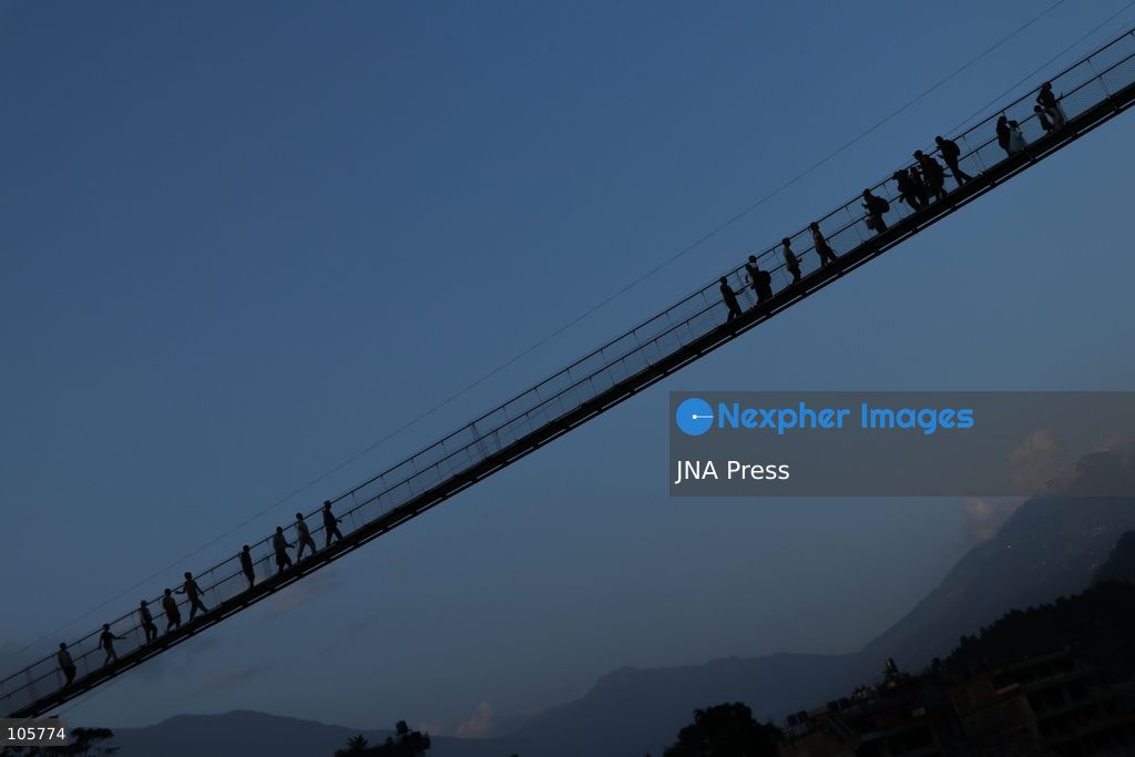 NUWAKOT, NEPAL, OCTOBER 14, 2026: Residents cross a newly built suspension bridge over the Trishuli River in Nuwakot, restoring access between communities affected by flash floods. Flooding destroyed bridges and damaged roads in the district, disrupting travel and access to essential services. Photo by Shankar Bhujel / JNA Press (Photo by Shankar Bhujel/JNA Press via Nexpher Images)