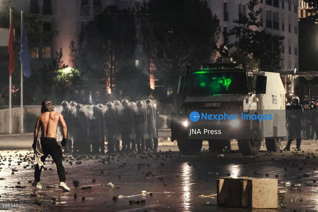 TIRANA, ALBANIA, OCTOBER 15, 2026: Students and other demonstrators protest near the Prime Minister’s Office in Tirana on the third consecutive day of anti-government demonstrations, demanding better university conditions and the resignation of Prime Minister Edi Rama. Clashes erupt between protesters and riot police, with demonstrators throwing stones, metal objects and pyrotechnics while officers respond with tear gas and water cannons. Fires are set in rubbish bins and at street kiosks, and damaged public property and debris are scattered across central Tirana. Some demonstrators are detained, while others help protesters affected by tear gas by pouring water over their faces to rinse their eyes. A bloodied female demonstrator is held on the ground by other protesters amid the confrontations. Photo by Vlasov Sulaj / JNA Press (Photo by Vlasov Sulaj/JNA Press via Nexpher Images)