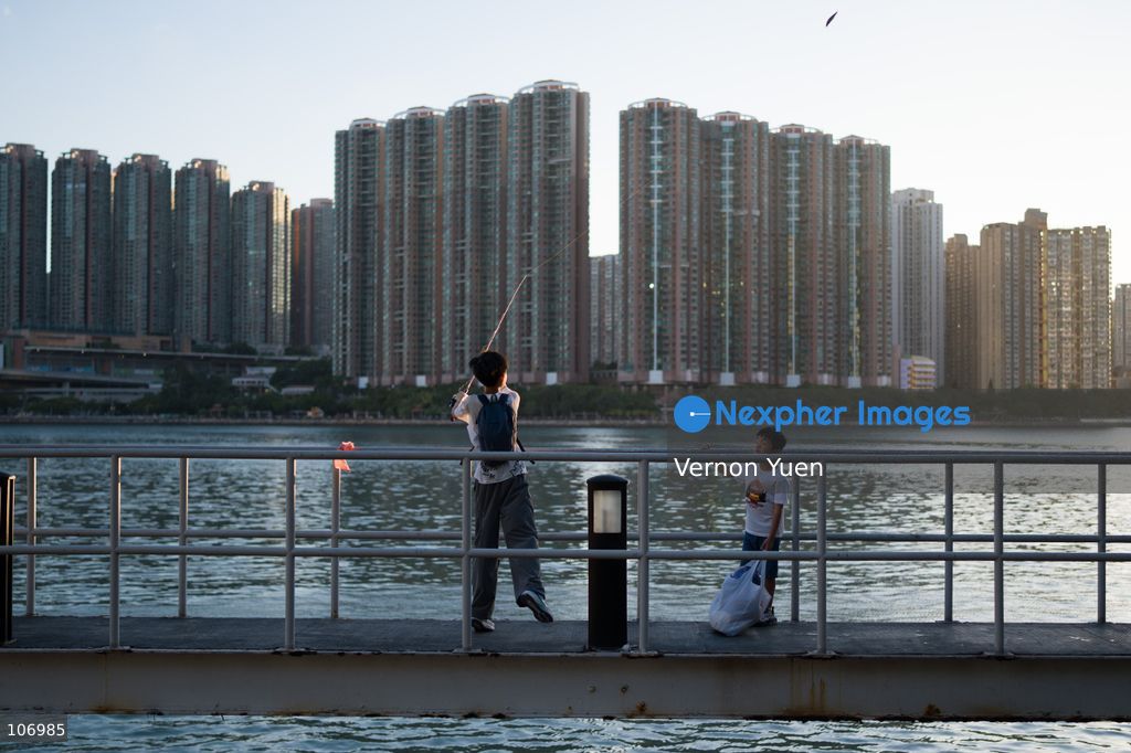 A boy fishing in font of residential housing buildings on October 18, 2026 in Hong Kong. (Photo by Vernon Yuen/Nexpher Images)