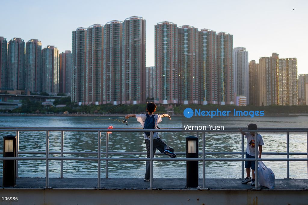 A boy fishing in font of residential housing buildings on October 18, 2026 in Hong Kong. (Photo by Vernon Yuen/Nexpher Images)
