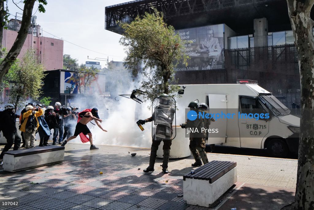 SANTIAGO, CHILE - OCTOBER 18, 2026: A person with their face covered is seen near Carabineros officers and an armored police vehicle amid a white cloud outside the GAM during the seventh anniversary of Chile's 2019 social uprising. (Photo by Pablo Zamorano/JNA Press via Nexpher Images)