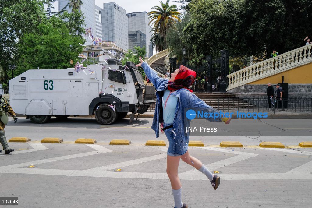SANTIAGO, CHILE - OCTOBER 18, 2026: A woman throws confetti into the air beside an armored Carabineros vehicle during the seventh anniversary of Chile's 2019 social uprising. (Photo by Pablo Zamorano/JNA Press via Nexpher Images)