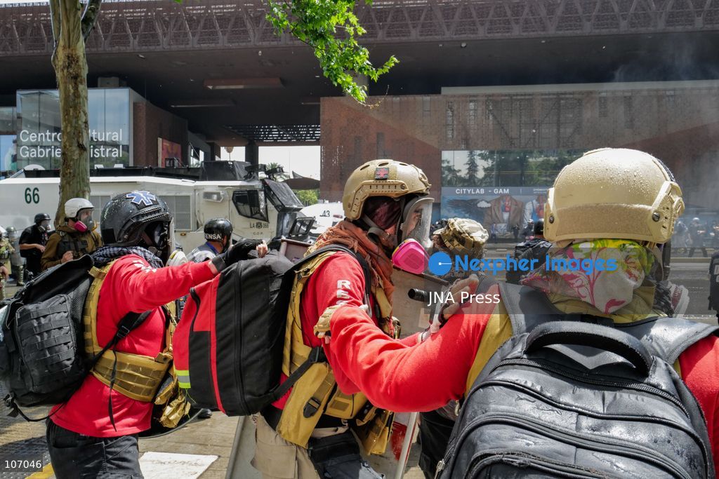 SANTIAGO, CHILE - OCTOBER 18, 2026: Members of a medical brigade wearing helmets and protective masks move near armored Carabineros vehicles outside the GAM during the seventh anniversary of Chile's 2019 social uprising. (Photo by Pablo Zamorano/JNA Press via Nexpher Images)