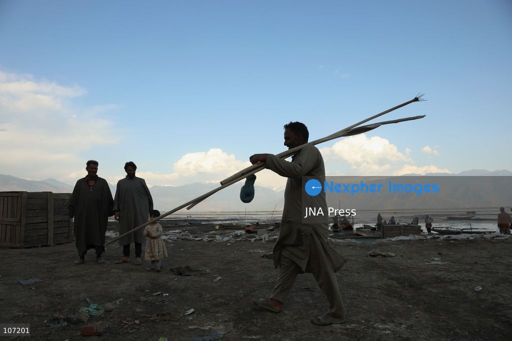 BANDIPORA, INDIA - OCTOBER 19, 2026: Fishermen cast their nets while women and other workers collect water chestnuts at Wular Lake in Bandipora district of Kashmir. Many families in the area earn their livelihoods from the lake's waters. (Photo by Kamran Yousuf/JNA Press via Nexpher Images)
