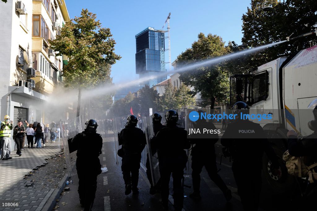 TIRANA, ALBANIA - OCTOBER 20, 2026: Anti-government protests continue in Tirana for an eighth consecutive day, with demonstrators gathering in central areas of the capital, including Skanderbeg Square. Protesters call for the resignation of Prime Minister Edi Rama, demanding improvements to university conditions and broader political change. Tensions escalate as Albanian riot police fire tear gas to disperse demonstrators. One protester collapses in Skanderbeg Square after tear gas is deployed. Amid the confrontations, a young demonstrator is also seen reaching out to shake hands with a riot police officer, offering a contrasting moment during the tense demonstrations. The protests reflect growing public discontent and continued tensions between demonstrators and the authorities. (Photo by Vlasov Sulaj/JNA Press via Nexpher Images)