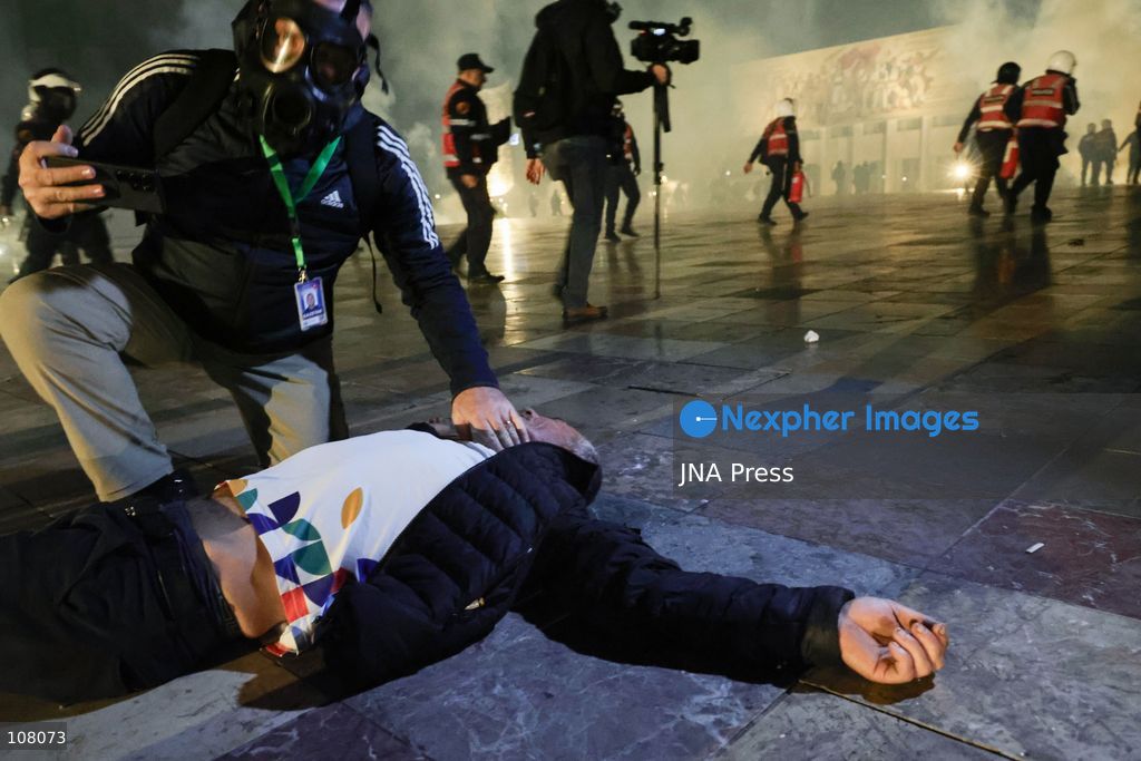TIRANA, ALBANIA - OCTOBER 20, 2026: Anti-government protests continue in Tirana for an eighth consecutive day, with demonstrators gathering in central areas of the capital, including Skanderbeg Square. Protesters call for the resignation of Prime Minister Edi Rama, demanding improvements to university conditions and broader political change. Tensions escalate as Albanian riot police fire tear gas to disperse demonstrators. One protester collapses in Skanderbeg Square after tear gas is deployed. Amid the confrontations, a young demonstrator is also seen reaching out to shake hands with a riot police officer, offering a contrasting moment during the tense demonstrations. The protests reflect growing public discontent and continued tensions between demonstrators and the authorities. (Photo by Vlasov Sulaj/JNA Press via Nexpher Images)