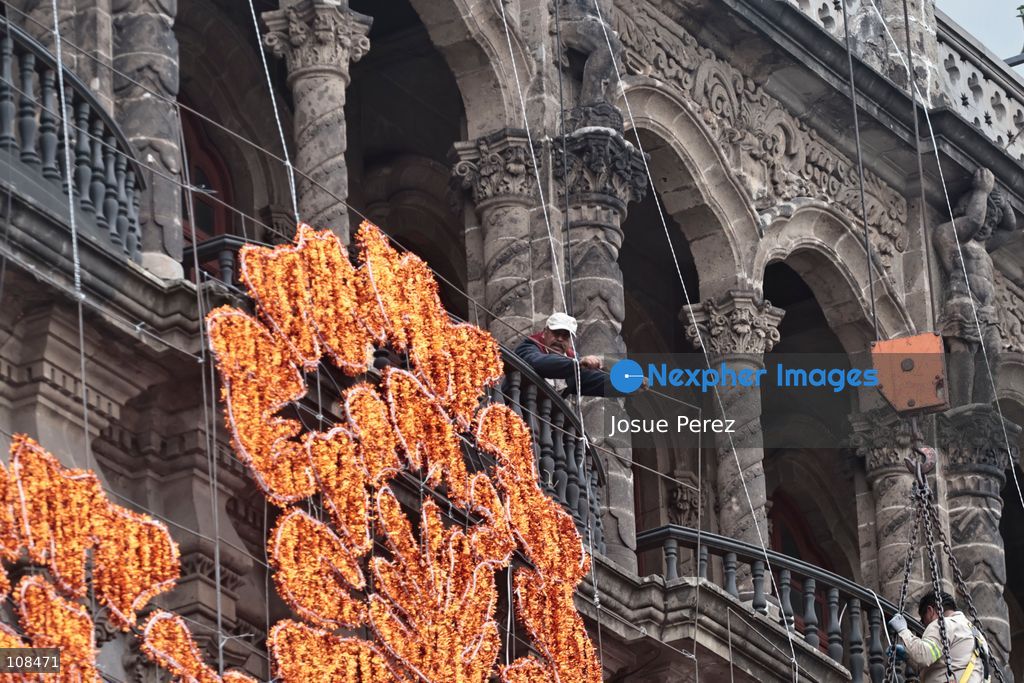 A worker is lifted in a crane to install and secure the lighting for the Day of the Dead on October 22, 2026, in Mexico City, Mexico. Construction crews working for the Mexico City government have begun assembling and installing the structures that will illuminate the buildings surrounding the city’s Zócalo. Using cranes, cables, and various framework components, they are preparing everything for the unveiling of the Monumental Ofrenda (altar), which will feature the world’s tallest Catrina, so that both locals and tourists can enjoy the start of the Day of the Dead celebrations in Mexico. (Photo by Josue Perez/Nexpher Images)