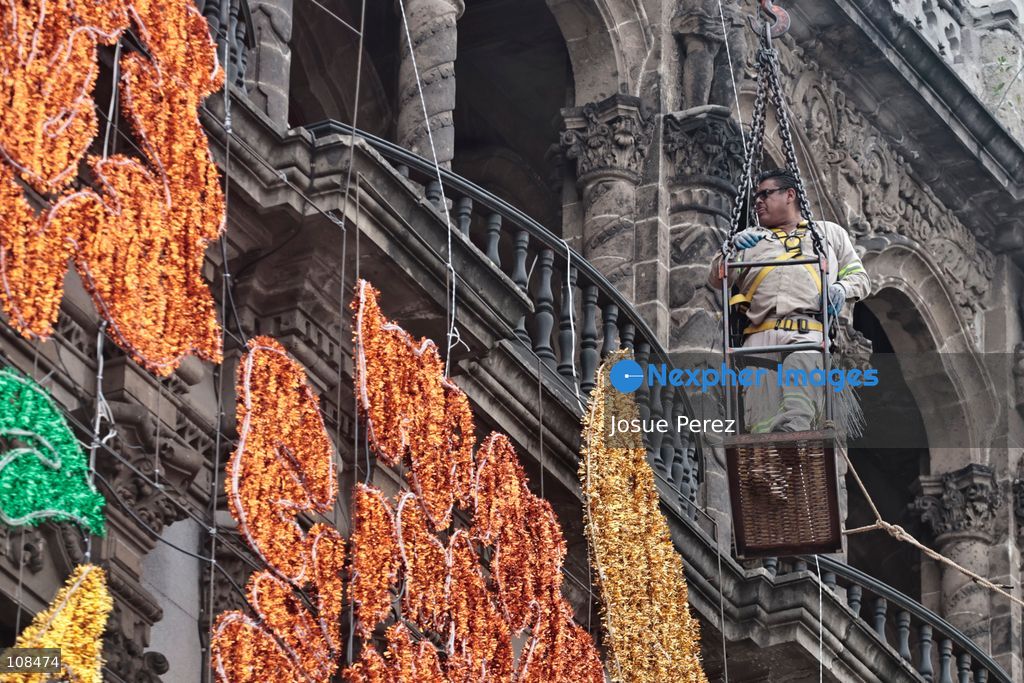 A worker is lifted in a crane to install and secure the lighting for the Day of the Dead on October 22, 2026, in Mexico City, Mexico. Construction crews working for the Mexico City government have begun assembling and installing the structures that will illuminate the buildings surrounding the city’s Zócalo. Using cranes, cables, and various framework components, they are preparing everything for the unveiling of the Monumental Ofrenda (altar), which will feature the world’s tallest Catrina, so that both locals and tourists can enjoy the start of the Day of the Dead celebrations in Mexico. (Photo by Josue Perez/Nexpher Images)