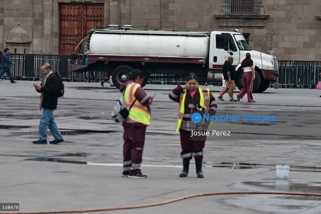 Cleaning workers wash and remove stains from the floor of the Plaza de la Constitución to prepare it for the installation of the monumental *ofrenda* (altar) and the world’s tallest *Catrina* figure, in celebration of the Day of the Dead, on October 22, 2026, in Mexico City, Mexico. Construction crews working for the Mexico City government have begun assembling and installing the structures that will illuminate the buildings surrounding the city’s Zócalo. Using cranes, cables, and various framework components, they are preparing everything for the unveiling of the Monumental Ofrenda (altar), which will feature the world’s tallest Catrina, so that both locals and tourists can enjoy the start of the Day of the Dead celebrations in Mexico. (Photo by Josue Perez/Nexpher Images)