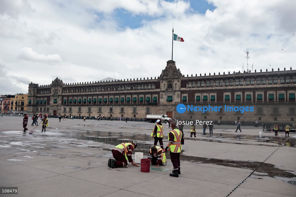 Cleaning workers wash and remove stains from the floor of the Plaza de la Constitución to prepare it for the installation of the monumental *ofrenda* (altar) and the world’s tallest *Catrina* figure, in celebration of the Day of the Dead, on October 22, 2026, in Mexico City, Mexico. Construction crews working for the Mexico City government have begun assembling and installing the structures that will illuminate the buildings surrounding the city’s Zócalo. Using cranes, cables, and various framework components, they are preparing everything for the unveiling of the Monumental Ofrenda (altar), which will feature the world’s tallest Catrina, so that both locals and tourists can enjoy the start of the Day of the Dead celebrations in Mexico. (Photo by Josue Perez/Nexpher Images)