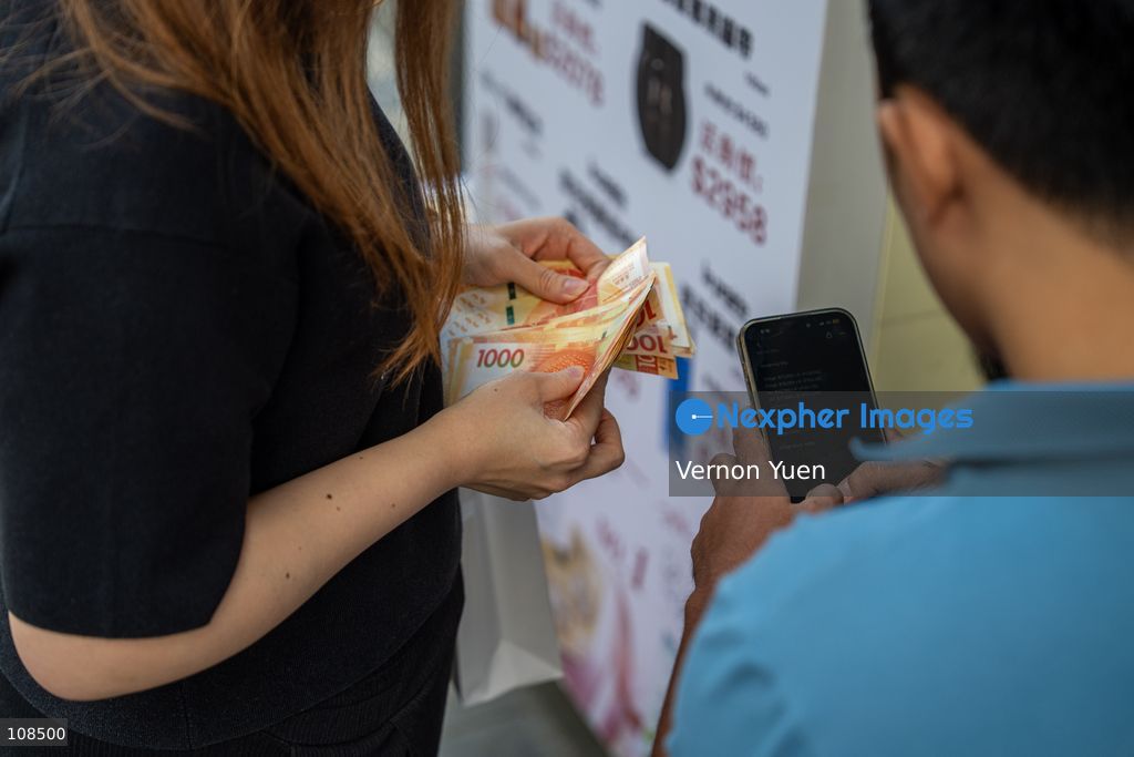 Iphone resellers counting money outside an Apple Store on October 22, 2026 in Hong Kong. The iPhone DUO is Apple INC.’s first foldable phone, today is the first day the new iPhone DUO is available to the public. (Photo by Vernon Yuen/Nexpher Images)