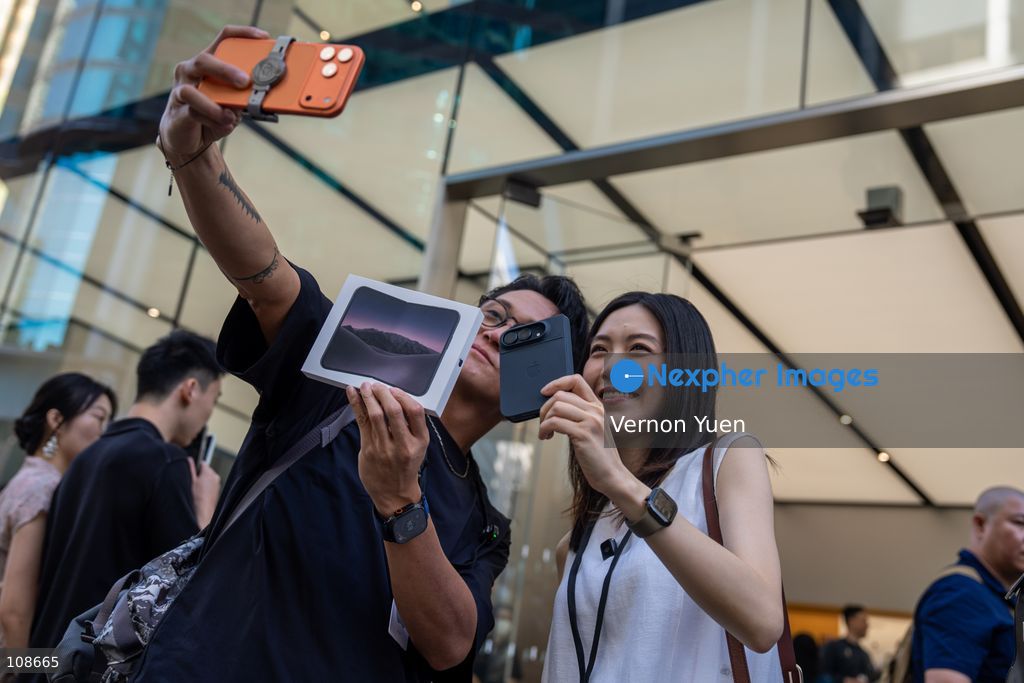 TOP PICS - A man wan a women talking a selfie holding iPhone Duo outside an Apple Store on October 22, 2026 in Hong Kong. The iPhone DUO is Apple INC.’s first foldable phone, today is the first day the new iPhone DUO is available to the public. (Photo by Vernon Yuen/Nexpher Images)