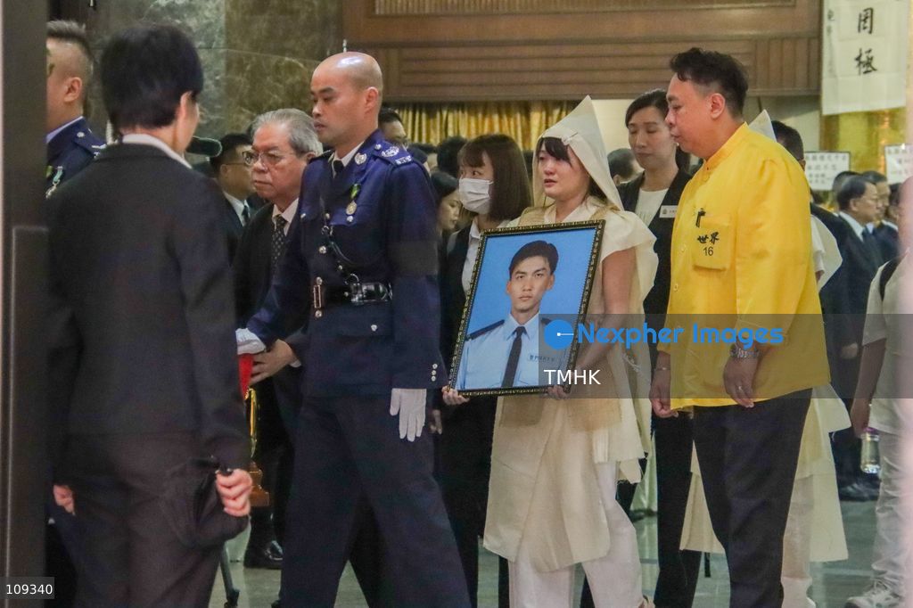 Family members carry a portrait of late police officer Chu Chun-kwok as they leave the funeral hall at the Universal Funeral Parlour in Hung Hom, Hong Kong, on October 23, 2026. (Photo by Gordon Choi/TMHK via Nexpher Images)