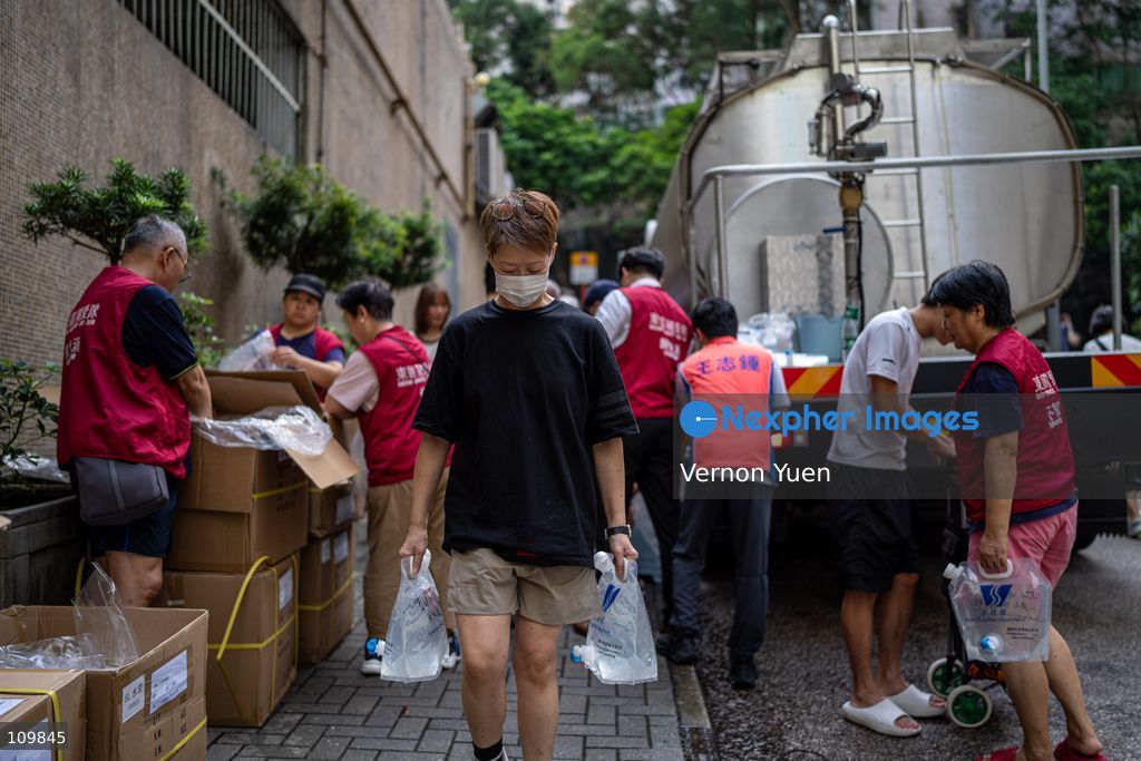 A woman holding plastic water containers after filling up at a water truck after a water main burst in Shau Kei Wan on October 27, 2026 in Hong Kong. (Photo by Vernon Yuen/Nexpher Images)