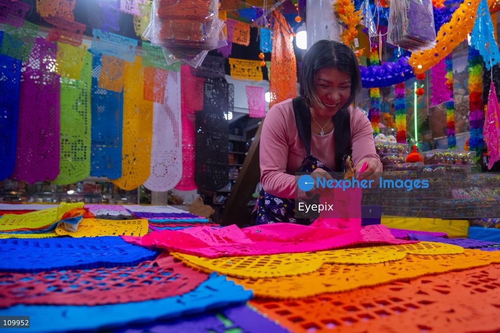 A vendor offers papel picado (traditional chiseled tissue paper) to customers preparing for the upcoming Day of the Dead (Dia de Muertos) celebrations at the Jamaica Marke on October 26, 2026 in Mexico City, Mexico. The traditional market experiences a massive influx of shoppers sourcing flowers, incense, sugar skulls, and altar decorations to honor their deceased loved ones ahead of the annual holiday celebrated on November 1 and 2. (Photo by Marko Gonzalez/ Eyepix Group/Eyepix via Nexpher Images)