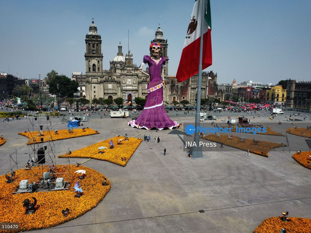 A monumental Catrina stands in Mexico City's Zócalo as the centerpiece of the 2026 Ofrenda Monumental. The roughly 32-meter figure, created by the Xibalbá art workshop, was unveiled as part of the Day of the Dead offering, which set a Guinness World Record for the tallest Catrina. The installation also features pieces from the exhibition "Ajolotes en el Corazón" and cempasúchil flowers. (Photo by Carlos Santiago/JNA Press via Nexpher Images)