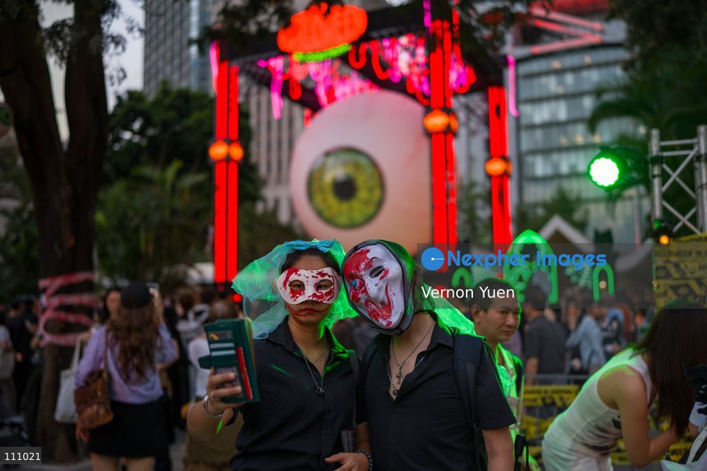 People dress in costumes taking a selfie with a large Eyeball display at a Halloween market in Central District on October 31, 2026 in Hong Kong. (Photo by Vernon Yuen/Nexpher Images)
