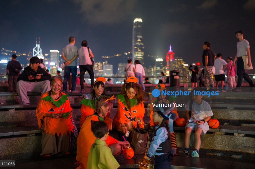 People dress in pumpkin costumes handing out candy to trick or treaters on October 31, 2026 in Hong Kong. (Photo by Vernon Yuen/Nexpher Images)