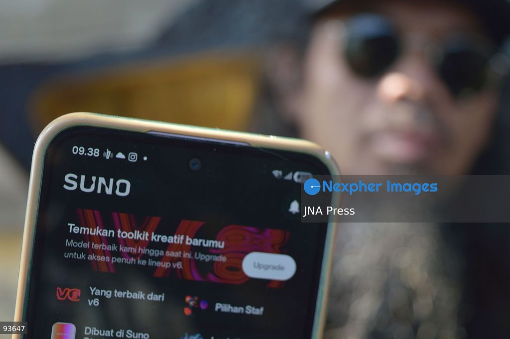 MEDAN, NORTH SUMATRA, INDONESIA, SEPTEMBER 17, 2026: The reflection of musician Jovan Siahaan, 42, appears on a smartphone displaying the Suno AI music platform as he arranges compositions for his digital solo project, Agent AI, in Medan, North Sumatra. Siahaan, who works as the project’s arranger and vocalist, uses artificial intelligence tools during the production process before adding his own vocal recordings to songs addressing social issues. The project is scheduled to perform at the Medanfor Thepunx #6 event. Photo by Sutanta Aditya / JNA Press. (Photo by Sutanta Aditya/JNA Press via Nexpher Images)