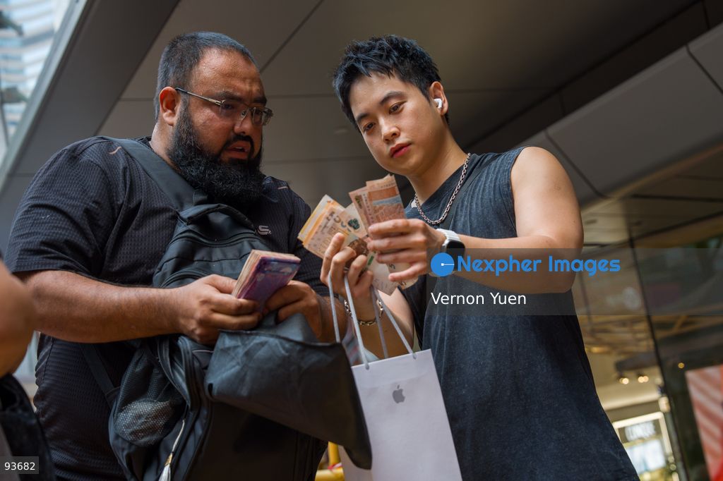 A man counting money next to an iphone reseller outside an apple store on the first day on sale of the iphone 18 pro on September 18, 2026 in Hong Kong. (Photo by Vernon Yuen/Nexpher Images)