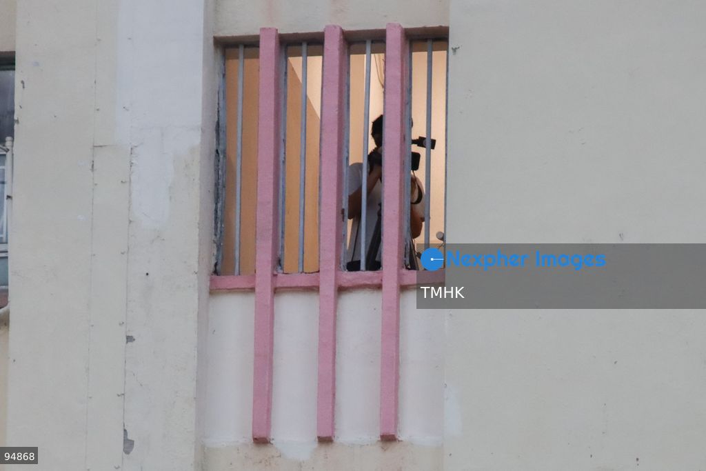 A telephoto view shows a television cameraman stationed on an upper-floor corridor of Model Housing Estate filming the exterior of the Hong Kong Funeral Home during the wake for former Chief Executive Tung Chee-hwa on September 19, 2026 in Hong Kong. (Photo by Gordon Choi/TMHK via Nexpher Images)