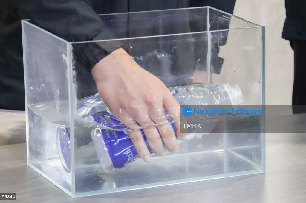 A close-up view shows a bottled drink submerged in water during a police demonstration at a press briefing on September 23, 2026 in Hong Kong. The demonstration aimed to show that tiny perforated holes on the packaging are designed as tear-away perforations rather than malicious syringe punctures. (Photo by Gordon Choi/TMHK via Nexpher Images)