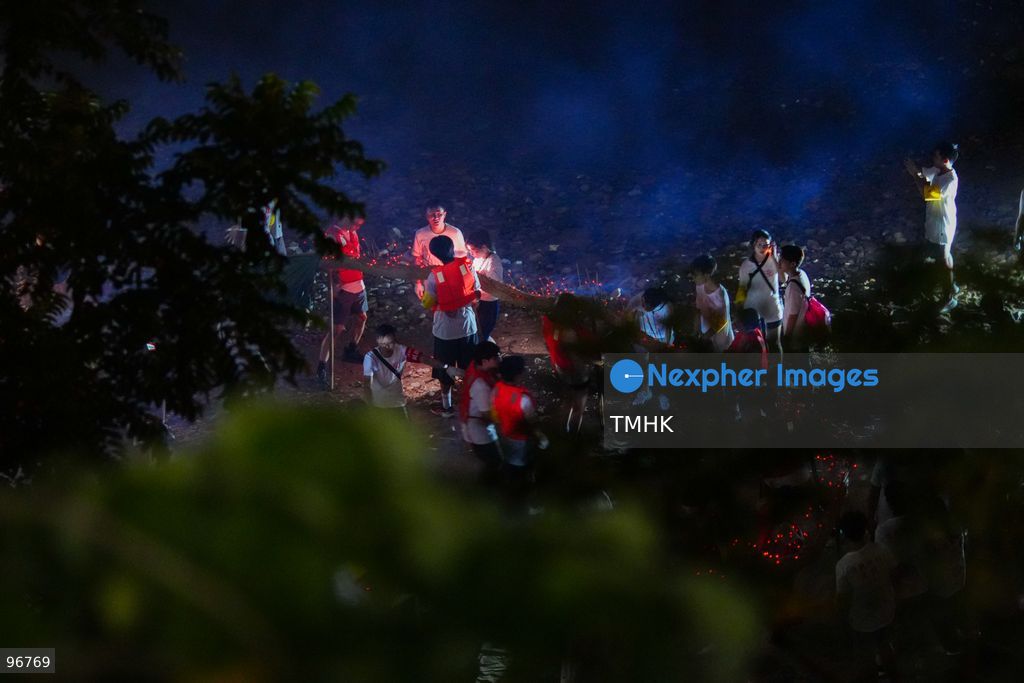 Villagers and performers wade into the waters off Waterfall Bay Park to submerge the 30-metre fire dragon in the sea on September 25, 2026 in Hong Kong, marking the sacred "Dragon Returning to the Sea" ritual as glowing incense sticks extinguish in the surf, signifying the successful completion of the Mid-Autumn blessings. (Photo by Zulu Lo/TMHK via Nexpher Images)