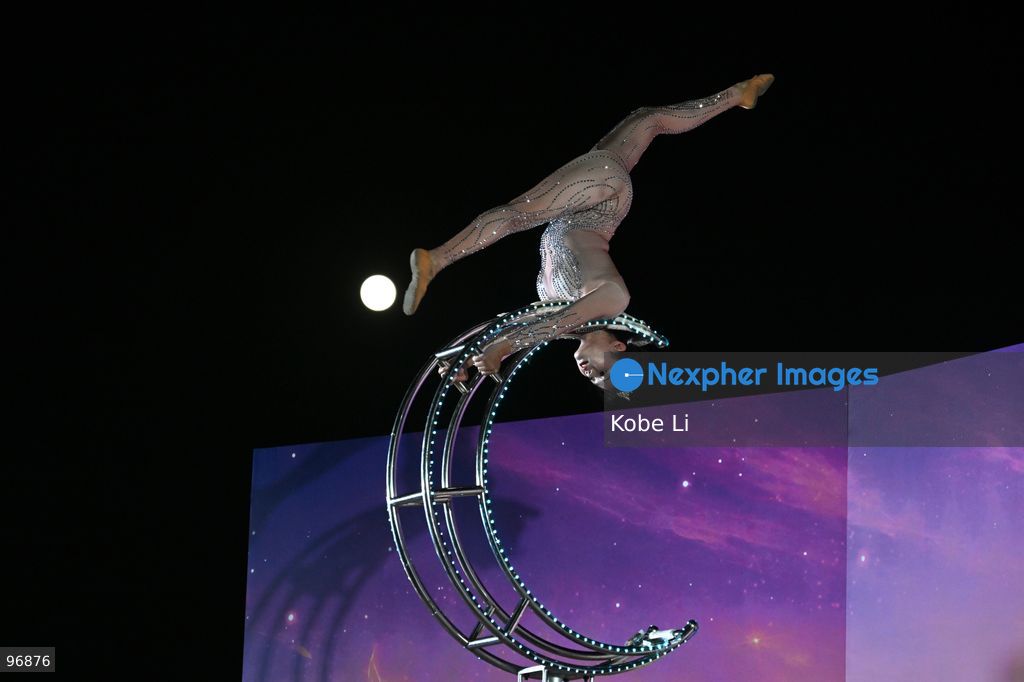 A performer executes a tumbling routine on a circular apparatus during a nighttime event and a moon is visible in the sky in Hung Hom New Waterfront the day after the Mid-Autumn Festival on September 26, 2026 in Hong Kong. (Photo by Kobe Li/Nexpher Images)