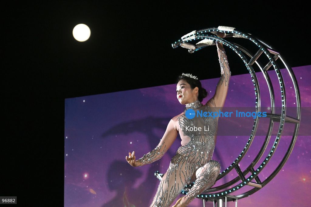 A performer executes a tumbling routine on a circular apparatus during a nighttime event and a moon is visible in the sky in Hung Hom New Waterfront the day after the Mid-Autumn Festival on September 26, 2026 in Hong Kong. (Photo by Kobe Li/Nexpher Images)