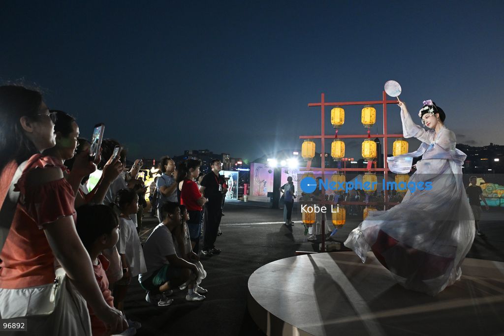 Visitors watch as a performer in traditional Hanfu attire performs in Hung Hom New Waterfront the day after the Mid-Autumn Festival on September 26, 2026 in Hong Kong. (Photo by Kobe Li/Nexpher Images)