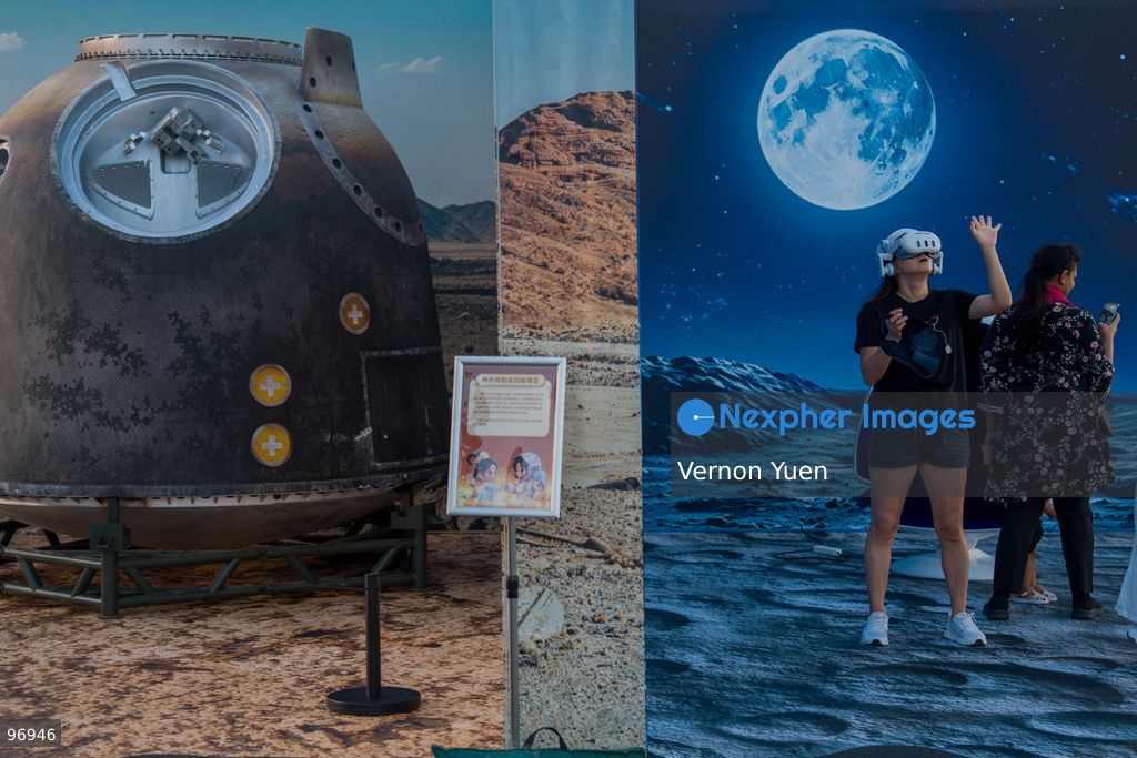 A woman wearing a VR headset next to a model of a chinese space capsule on September 26, 2026 in Hong Kong. (Photo by Vernon Yuen/Nexpher Images)