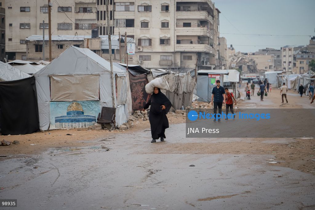 GAZA CITY, GAZA STRIP, SEPTEMBER 29, 2026: Palestinians walk through rain-soaked streets surrounded by destroyed buildings and tents sheltering displaced families in Gaza City. The arrival of rainy weather is adding to difficult living conditions for displaced Palestinians, many of whom remain in tents and makeshift shelters with limited protection from the elements.  Photo by Mohammed M. Skaik / JNA Press. (Photo by Mohammed M Skaik/JNA Press via Nexpher Images)