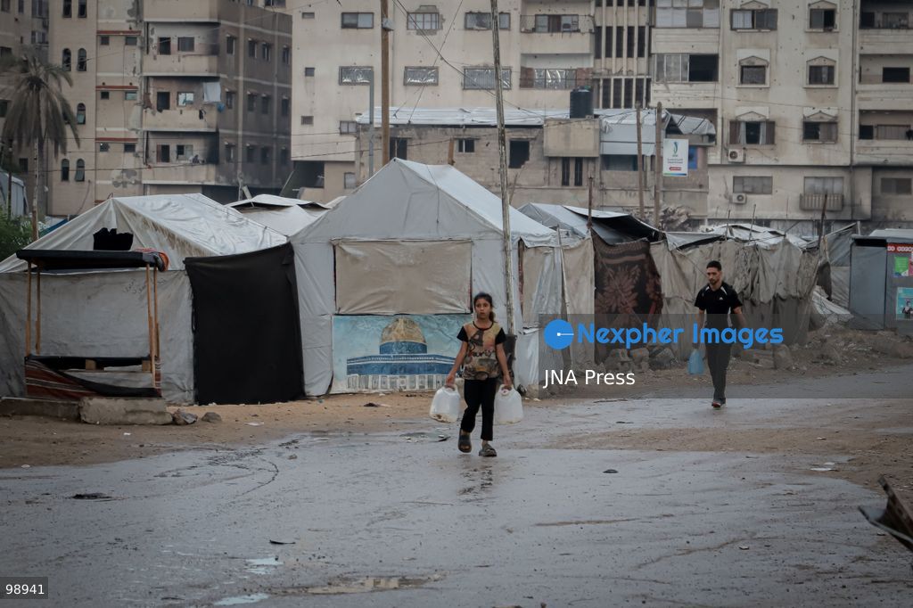 GAZA CITY, GAZA STRIP, SEPTEMBER 29, 2026: Palestinians walk through rain-soaked streets surrounded by destroyed buildings and tents sheltering displaced families in Gaza City. The arrival of rainy weather is adding to difficult living conditions for displaced Palestinians, many of whom remain in tents and makeshift shelters with limited protection from the elements. Photo by Mohammed M. Skaik / JNA Press. (Photo by Mohammed M Skaik/JNA Press via Nexpher Images)