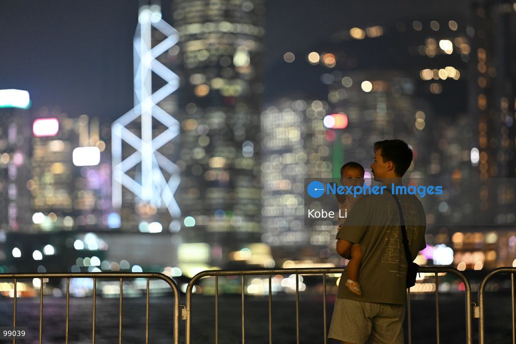 A man holds his child while looking out at the illuminated skyline of Hong Kong at night on September 29, 2026 in Hong Kong. (Photo by Kobe Li/Nexpher Images)