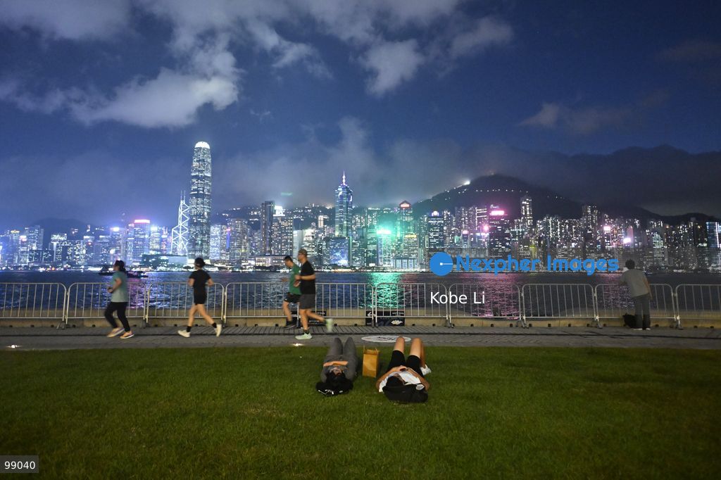 People relax and exercise along a waterfront promenade as the illuminated skyline of Hong Kong glows at dusk on September 29, 2026 in Hong Kong. (Photo by Kobe Li/Nexpher Images)