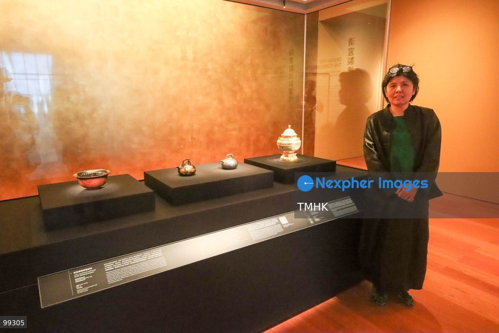 A guest poses for photographs beside rare artefacts during the press preview for "Design for the Forbidden City: Imperial Workshops of the Qing Court" in Gallery 5 of the Hong Kong Palace Museum on September 29, 2026 in Hong Kong. The showcase features 14 grade-one national treasures illuminating the distinct aesthetic visions of the Kangxi, Yongzheng, and Qianlong emperors. (Photo by Gordon Choi/TMHK via Nexpher Images)